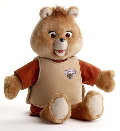 teddy ruxpin - a toy bear with animatronic mouth and eyes, wears a brown shirt