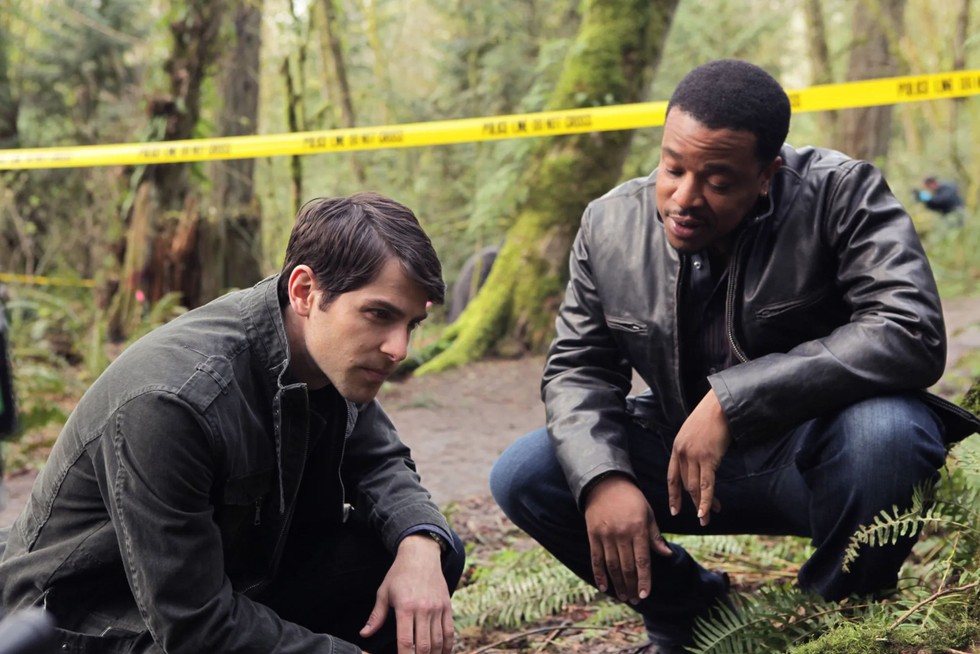 Left to right Nick Burkhardt and Hank Griffin crouching down to look at something - Grimm