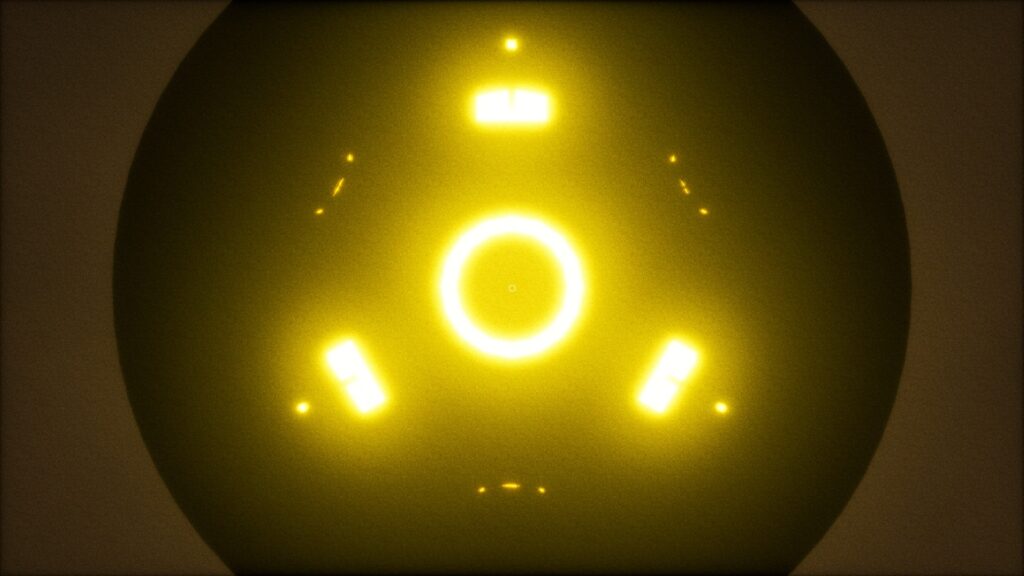 UFOPHILIA - The underside of a UFO. A yellow circle at its centre and three small disjointed lines making the shape of a triangle outside the circle are all illuminated in a bright yellow light, a dark cloudy sky is in the background.