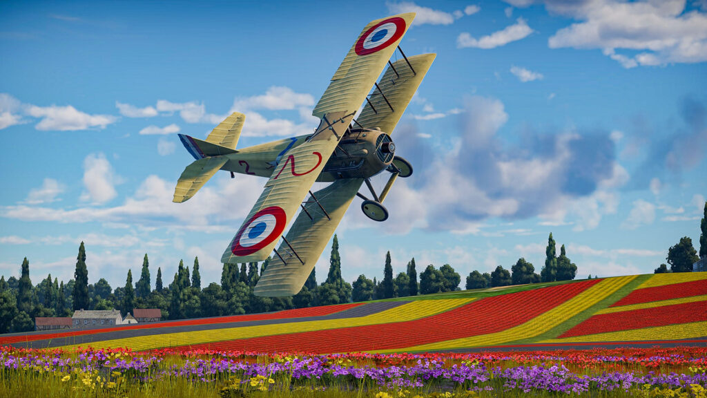 Aces of Thunder - A French Nieuport 11 biplane banking over a colorful, multi-colored flower field